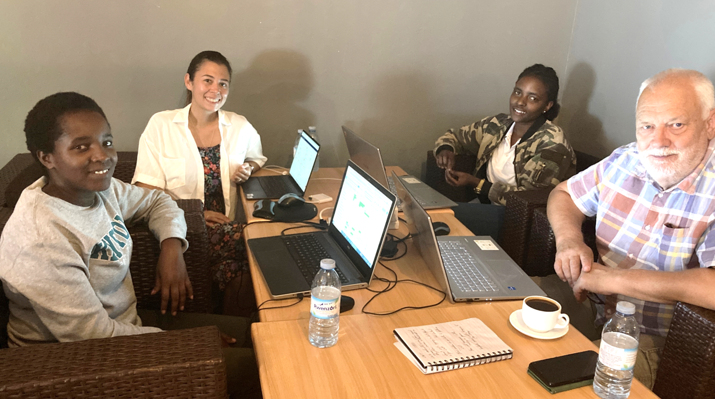 Four colleagues working together around a table with laptops